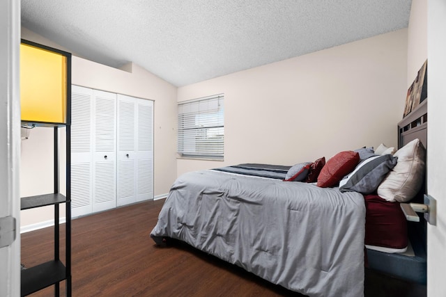 bedroom with a textured ceiling, a closet, dark wood-type flooring, and lofted ceiling