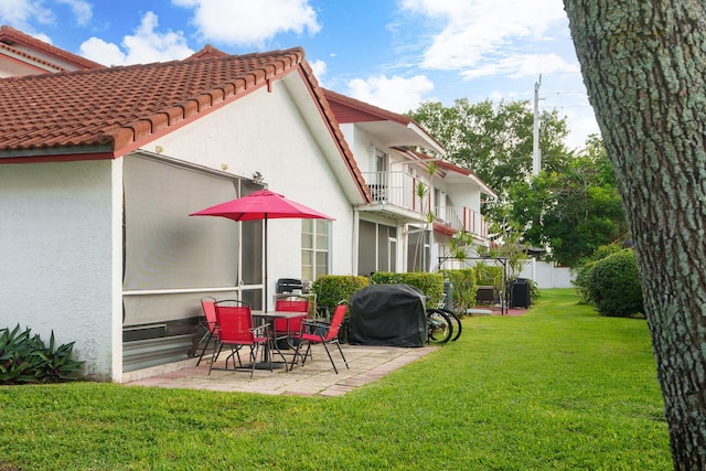 rear view of property with a patio area, a yard, and a balcony