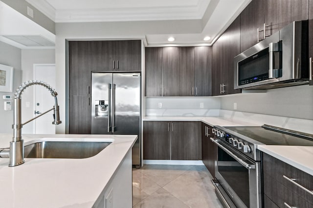 kitchen with appliances with stainless steel finishes, dark brown cabinetry, ornamental molding, and sink