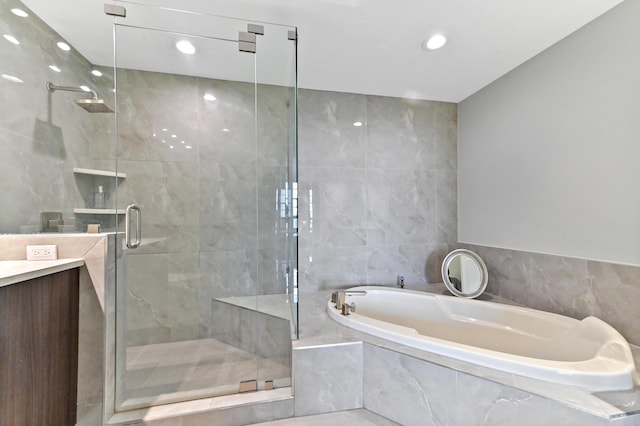 bathroom featuring vanity, tile walls, and independent shower and bath