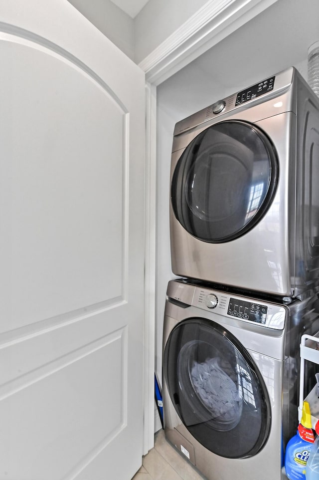 laundry area featuring stacked washing maching and dryer and light tile patterned floors