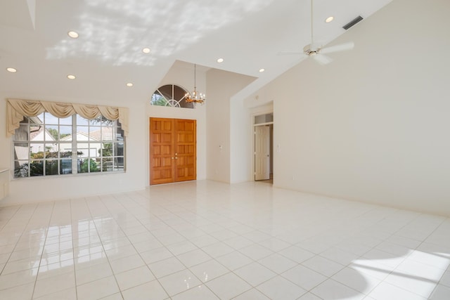 tiled spare room featuring ceiling fan with notable chandelier and high vaulted ceiling