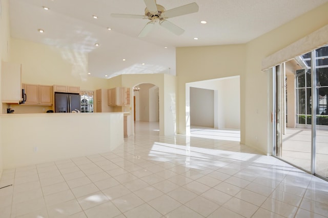 empty room featuring a high ceiling, light tile patterned floors, and ceiling fan