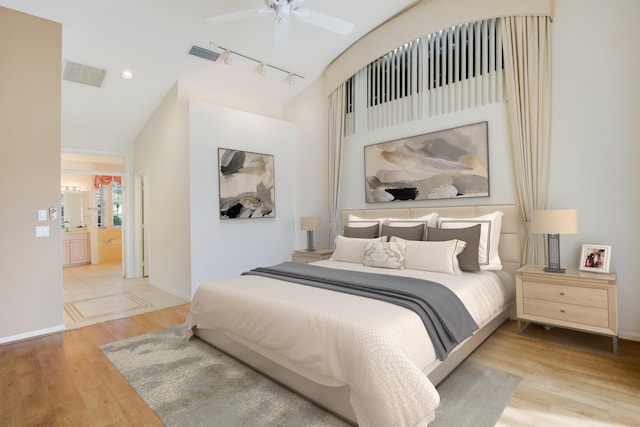 bedroom featuring ceiling fan, ensuite bathroom, light wood-type flooring, and rail lighting