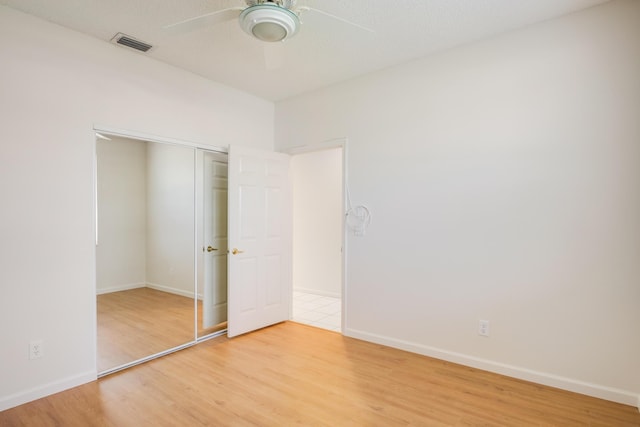 unfurnished bedroom with hardwood / wood-style floors, ceiling fan, and a closet