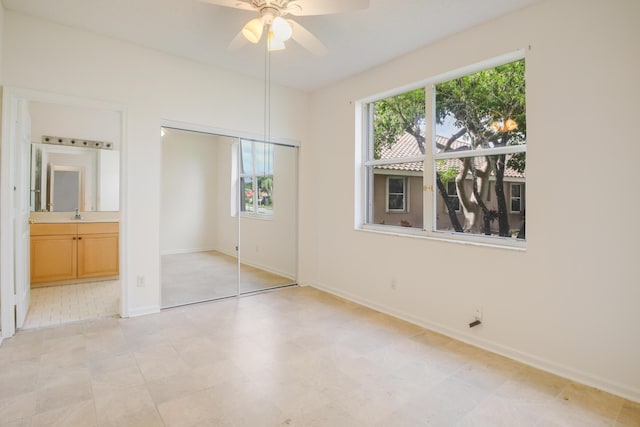 unfurnished bedroom with ensuite bathroom, sink, and ceiling fan