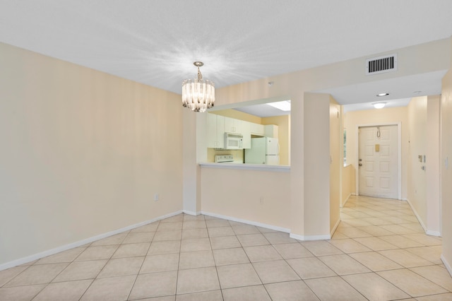 spare room featuring a notable chandelier and light tile patterned floors