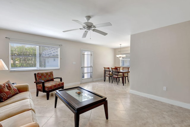 living room with ceiling fan with notable chandelier and light tile patterned floors