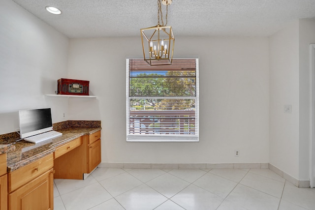 1260 NW 20th Ave Unit 203, Delray Beach, FL 33445 - unfurnished dining area with a wealth of natural light, a textured ceiling, built in study area, and an inviting chandelier