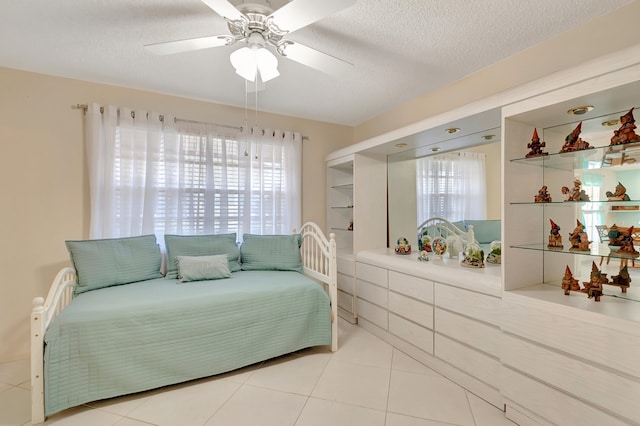 tiled bedroom with a textured ceiling and ceiling fan