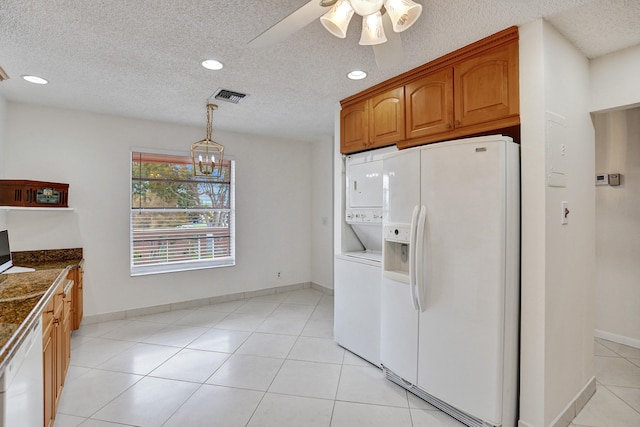 1260 NW 20th Ave Unit 203, Delray Beach, FL 33445 - kitchen with stacked washing maching and dryer, white appliances, brown cabinets, visible vents, and a textured ceiling
