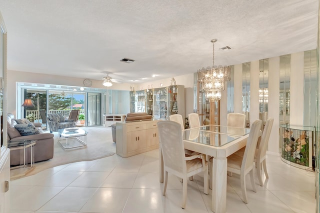 tiled dining area featuring ceiling fan with notable chandelier and a textured ceiling