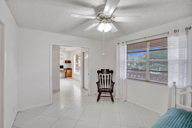 1260 NW 20th Ave Unit 203, Delray Beach, FL 33445 - living area featuring baseboards, light tile patterned floors, a ceiling fan, and a textured ceiling
