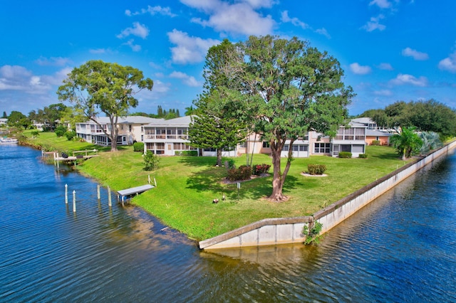 view of dock with a lawn and a water view