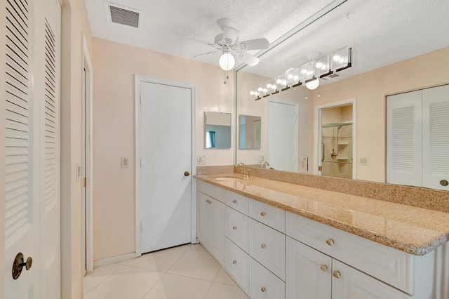 bathroom with ceiling fan, tile patterned flooring, vanity, and a textured ceiling