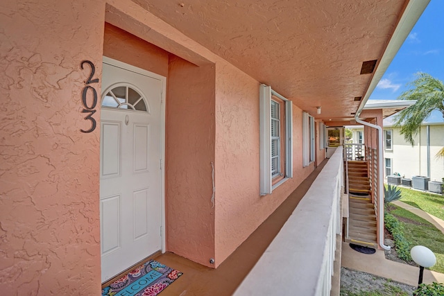 1260 NW 20th Ave Unit 203, Delray Beach, FL 33445 - doorway to property with stucco siding and central AC unit