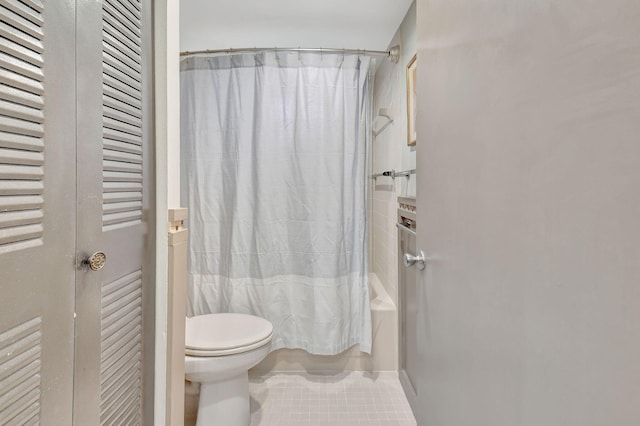 bathroom with tile patterned floors, shower / bath combination with curtain, and toilet