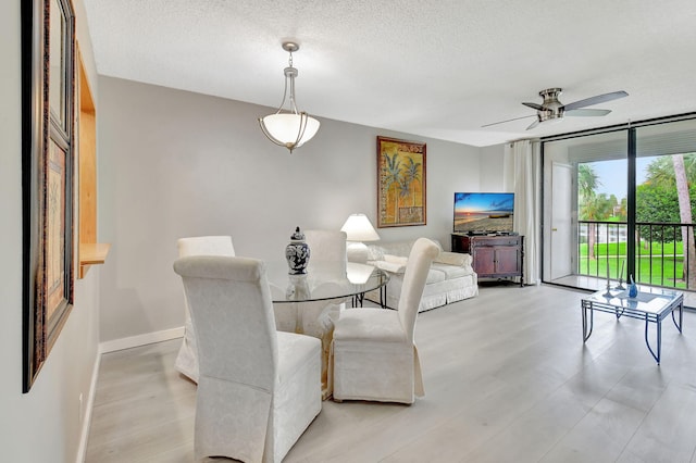 dining space featuring ceiling fan, light wood-type flooring, and a textured ceiling