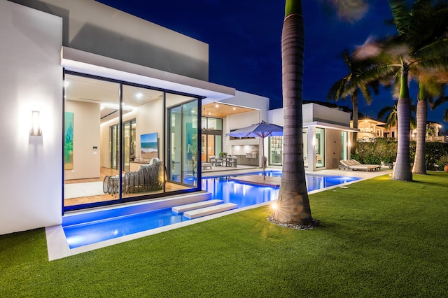 pool at night with a lawn and a patio area