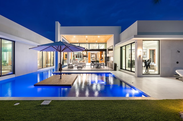 pool at night featuring an outdoor hangout area and a yard