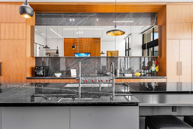 kitchen featuring decorative backsplash, decorative light fixtures, and dark stone countertops