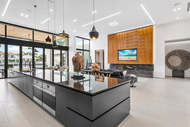 interior space featuring a spacious island, hanging light fixtures, sink, and dark stone countertops