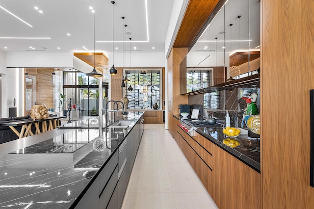 kitchen with sink, tasteful backsplash, dark stone countertops, decorative light fixtures, and stainless steel gas stovetop