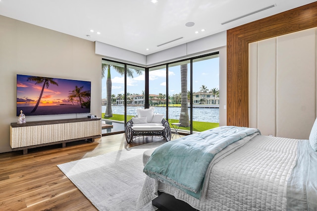 bedroom featuring access to exterior, a water view, and wood-type flooring