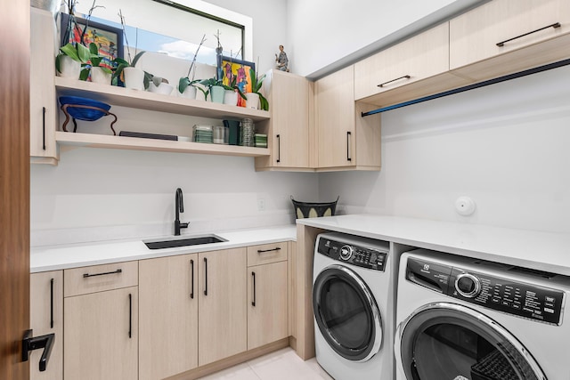 laundry area with cabinets, sink, washer and dryer, and light tile patterned flooring