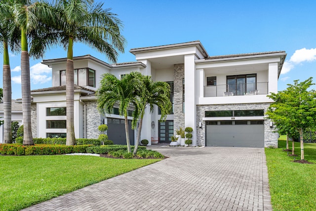 view of front of house with a garage, a front yard, and a balcony