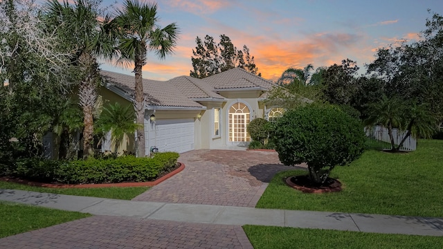 mediterranean / spanish-style house with a garage and a lawn