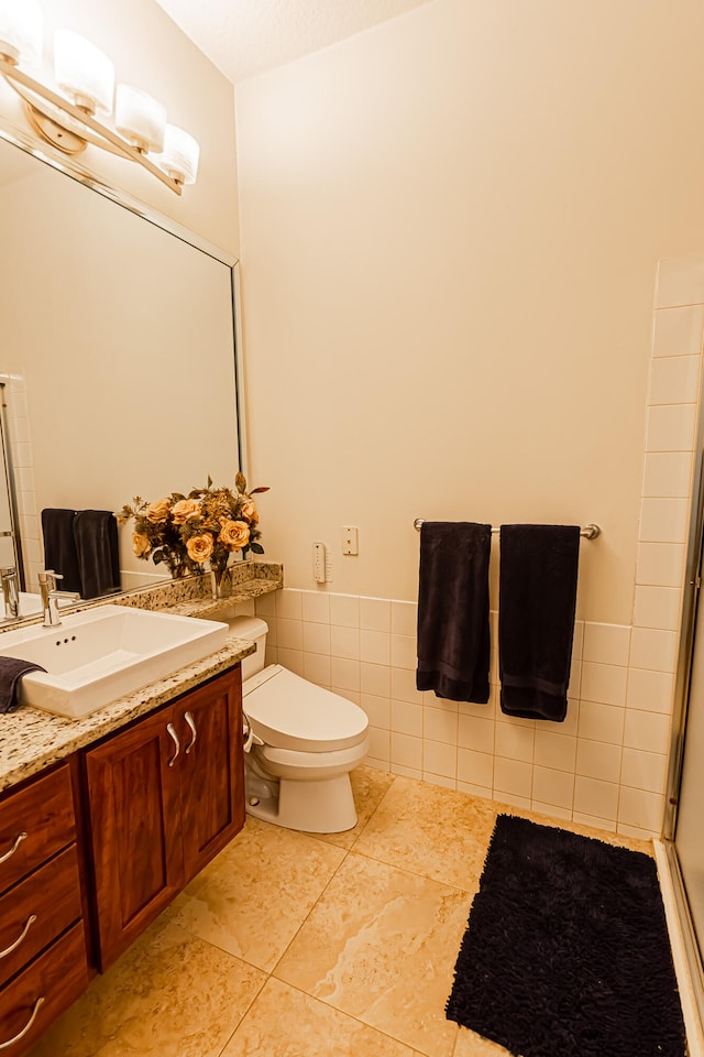 bathroom with tile walls, tile patterned flooring, vanity, an enclosed shower, and toilet