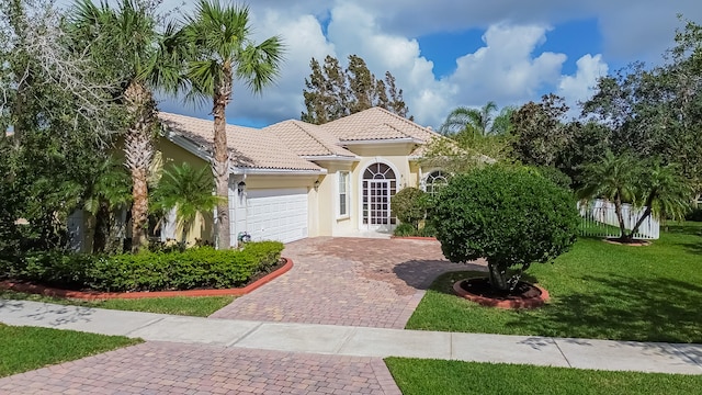 mediterranean / spanish-style home featuring a garage and a front lawn