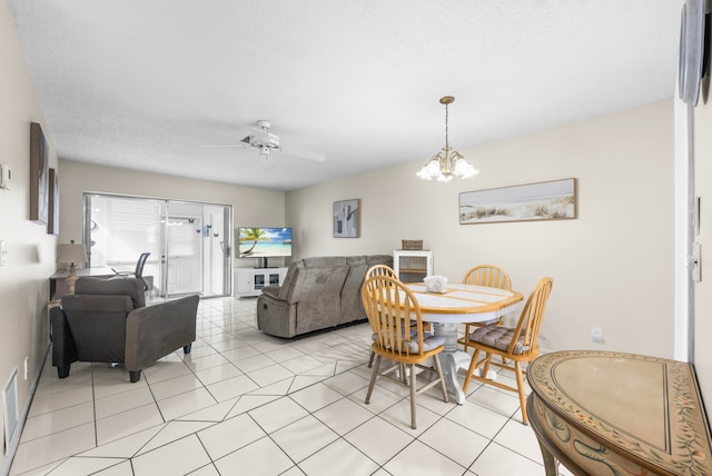 tiled dining area with ceiling fan with notable chandelier and a textured ceiling