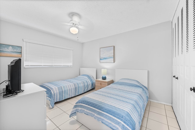 bedroom featuring a closet, a textured ceiling, light tile patterned floors, and ceiling fan