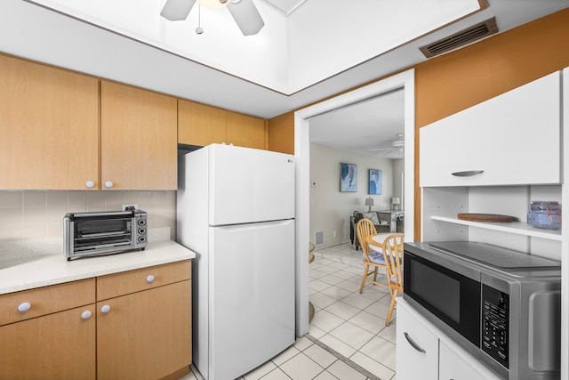 kitchen with ceiling fan, light tile patterned floors, white refrigerator, and tasteful backsplash