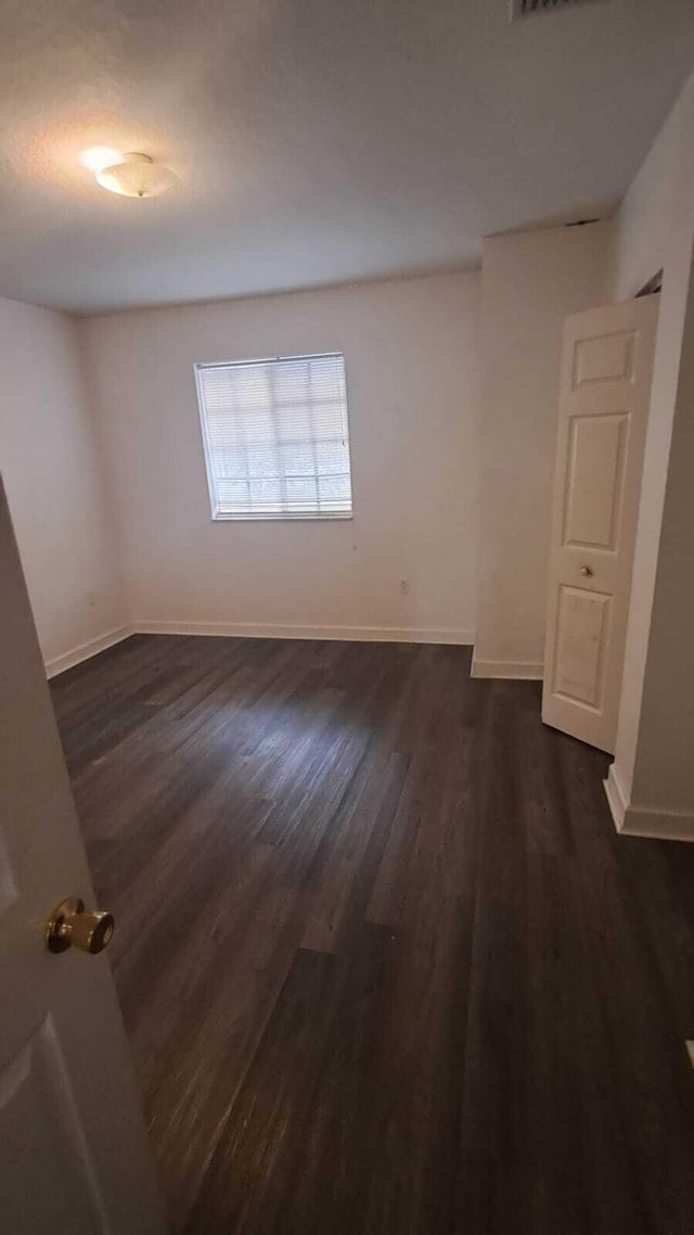 unfurnished room featuring dark wood-type flooring