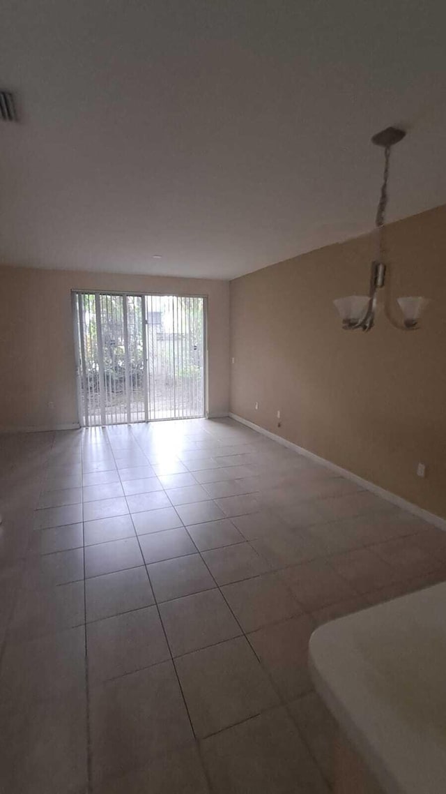 empty room with tile patterned floors and a notable chandelier