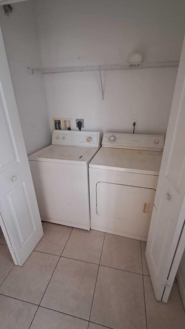 clothes washing area with washing machine and dryer and light tile patterned floors