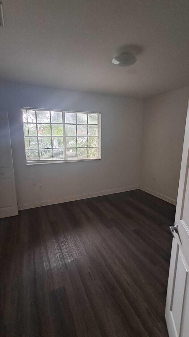 empty room with dark hardwood / wood-style floors and plenty of natural light