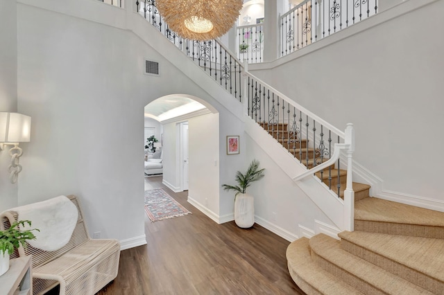 stairway with a towering ceiling and hardwood / wood-style floors