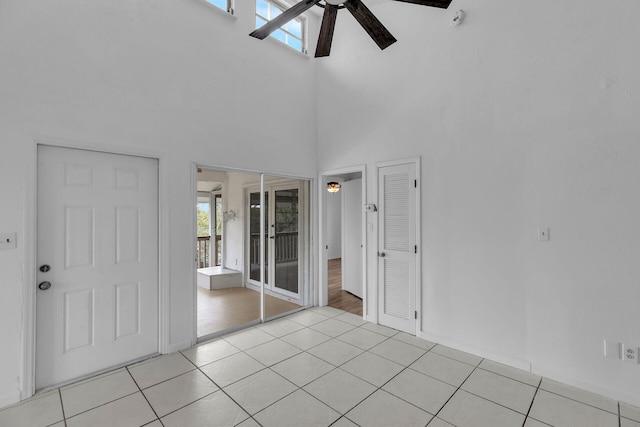 spare room featuring ceiling fan, a towering ceiling, and light tile patterned floors