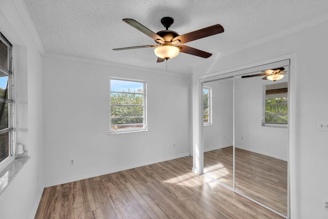 unfurnished bedroom featuring a textured ceiling, multiple windows, and wood finished floors