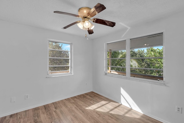 empty room with a textured ceiling, ceiling fan, baseboards, and light wood-style floors