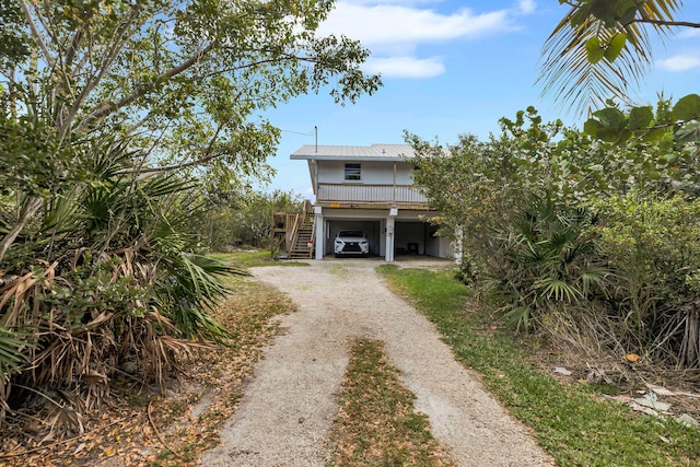 view of front of house featuring dirt driveway, a carport, stairway, and metal roof