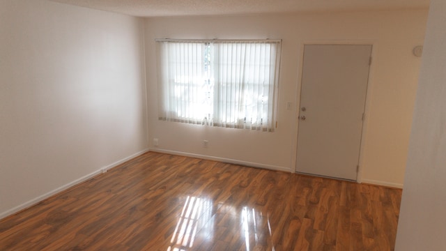 empty room with a textured ceiling and dark hardwood / wood-style flooring