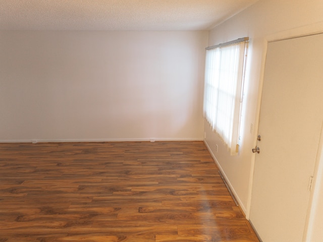 unfurnished room with dark hardwood / wood-style flooring and a textured ceiling