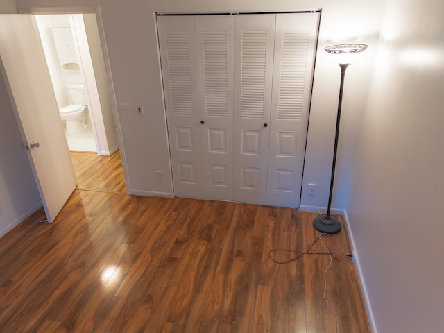 unfurnished bedroom with dark hardwood / wood-style flooring and a closet