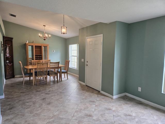 dining area with a chandelier, light tile patterned floors, and vaulted ceiling