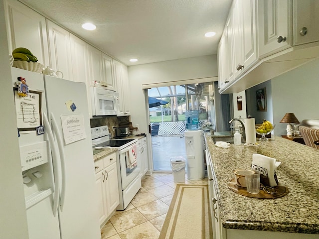 kitchen featuring light stone countertops, white appliances, white cabinetry, and sink